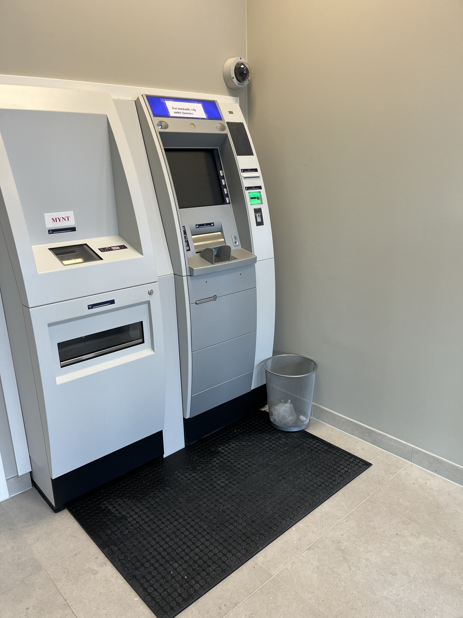 Her har vi levert en trykkfølsom matte fra Bircher til en lokal minibank. Når en bruker står på matten deaktiveres utvendig bryter så ikke andre kan komme inn. Det blinker også et rødt lys som indikerer at minibanken er opptatt. Vi har også levert et astrour som deaktiverer utvendig bryter utenfor minibankens åpningstid.
